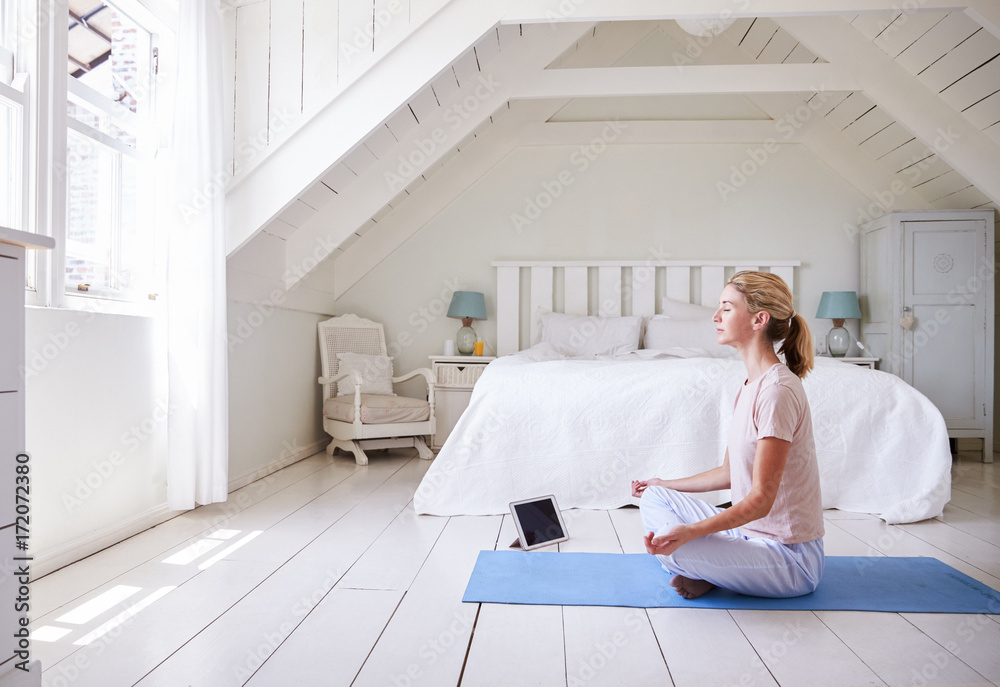 Woman With Digital Tablet Using Meditation App In Bedroom - obrazy, fototapety, plakaty 