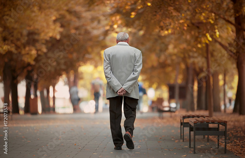 Old man walking in autumn park photo