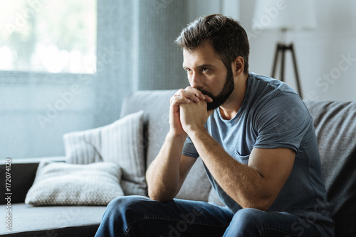 Canvastavla Unhappy bearded man sitting on the sofa