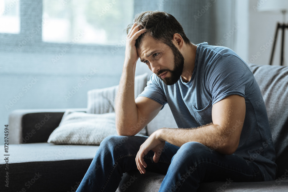 Sad gloomy man holding his forehead