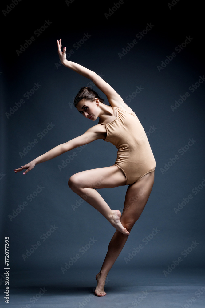 Fototapeta premium A beautiful athletic girl in a black dress is dancing. In move