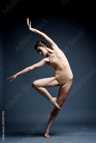 Fototapeta Naklejka Na Ścianę i Meble -  A beautiful athletic girl in a black dress is dancing. In move
