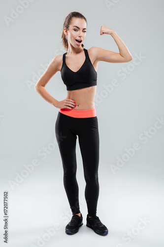 Full length portrait of a young sportswoman flexing muscles © Drobot Dean