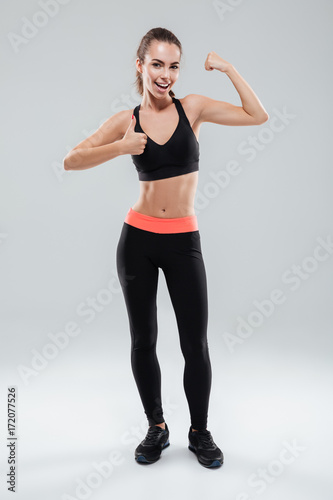 Full length portrait of a young sportswoman flexing muscles