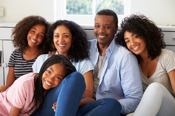 Portrait Of Smiling Family Relaxing On Seat At Home