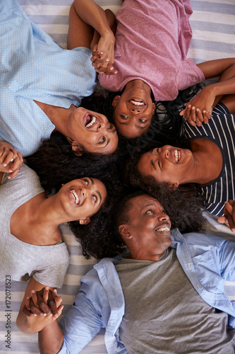 Overhead View Of Family With Teenage Children Lying On Bed