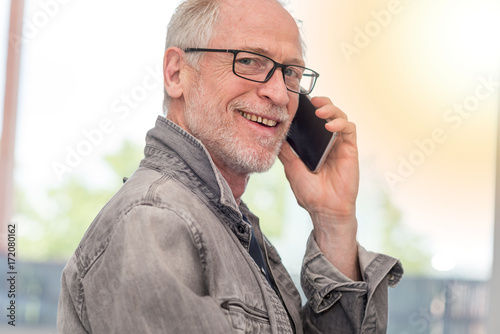 Portrait of smiling mature man talking on phone, light effect