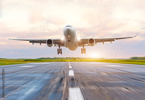 Passenger airplane landing at sunset on a runway