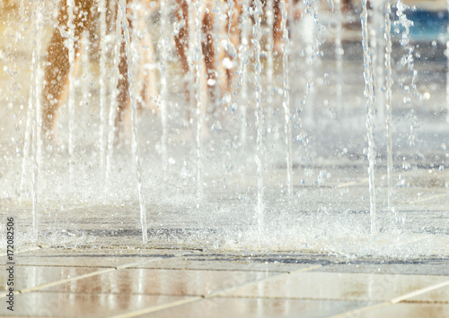 Children having fun in small fountains at hot summer.