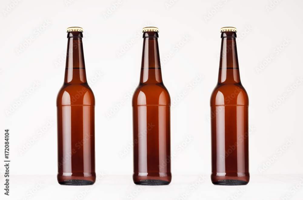 Three brown longneck beer bottles mock up. Template on white wood table.
