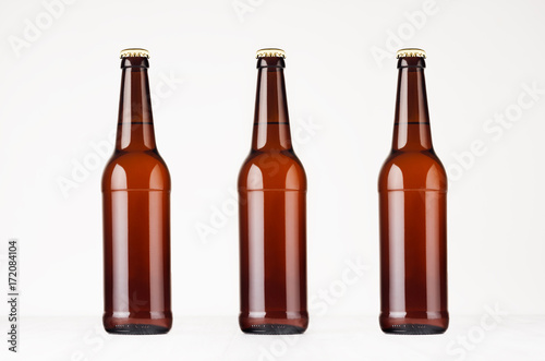 Three brown longneck beer bottles mock up. Template on white wood table.