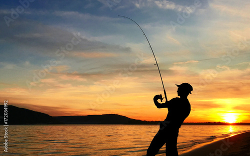Young man fishing at sunset