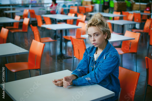 young beautiful woman in jeans clothes in business space of shopping center. portrait of a girl with freckles on her face, stylish girl in an empty cafe