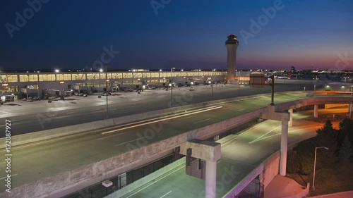 Detroit MI DTW Airport Early Morning Timelapse with Arriving Vehicle Traffic with Light Streaks from Driving Cars and the Air Control Tower in a Vibrant Colorful Sky Background