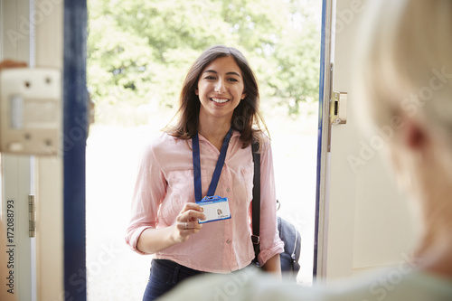 Female care worker on home visit showing her ID, close up