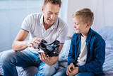 Pleasant father showing his son new VR headset