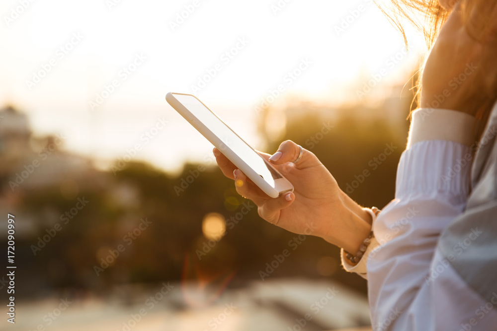 Cropped image of woman in autumn clothes usin her smartphone