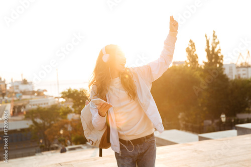 Cheereful brunette woman in autumn clothes listening music and dancing