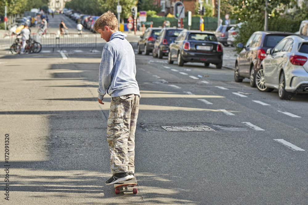 Young teenager boy practice skateboarding during the Car Free Streets day