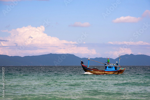 Fishing boat on a sunny day in the ocean on a background of mountains