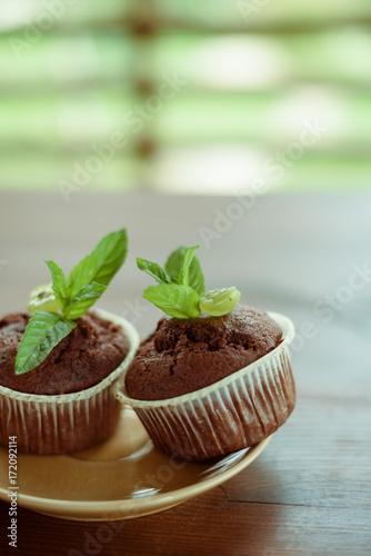 Fototapeta Naklejka Na Ścianę i Meble -  Morning breakfast: two chocolate muffins with mint on a wooden table.