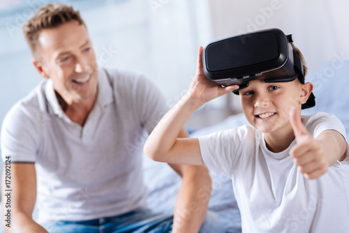 Happy boy wearing VR headset and showing thumbs up