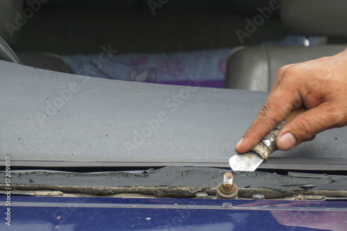 Glazier using tools repairing to fix crack broken windshield, windscreen on the front window glass of the machine car accident.