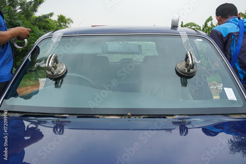 Glazier using tools repairing to fix crack broken windshield, windscreen on the front window glass of the machine car accident.