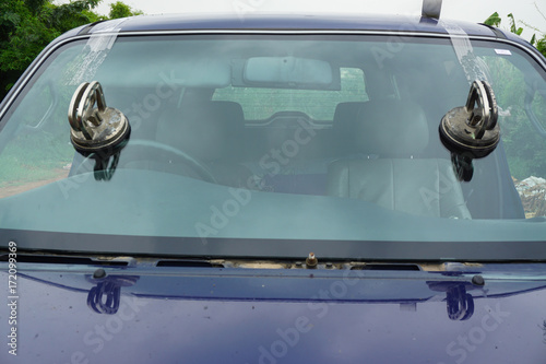 Glazier using tools repairing to fix crack broken windshield, windscreen on the front window glass of the machine car accident.