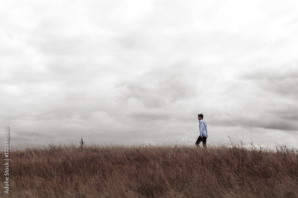man who feels free in a field on a hill