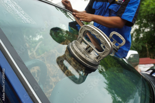 Glazier using tools repairing to fix crack broken windshield, windscreen on the front window glass of the machine car accident.
