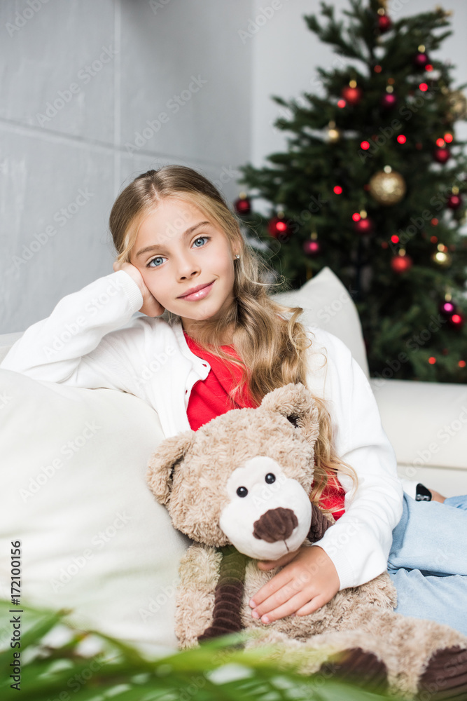 child with teddy bear at christmas tree
