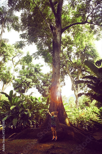 young caucasian woman jumping from root of big tree, Brazil