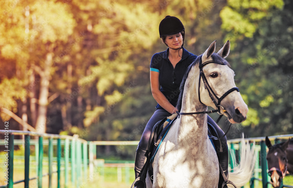 Young woman riding a horse, jockey in sport wear