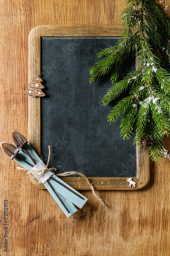 Vintage empty chalkboard with fir Christmas tree and wood modern decor skiing over wooden background. Top view with space for text