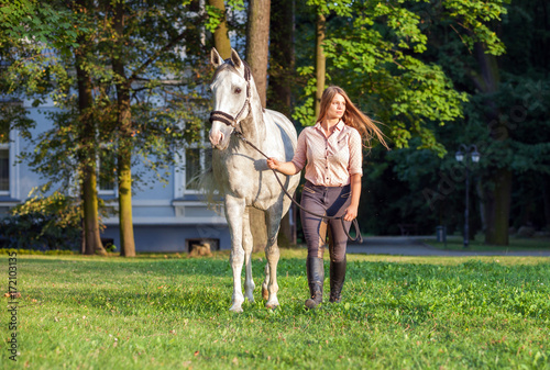Woman walking with her horse across park