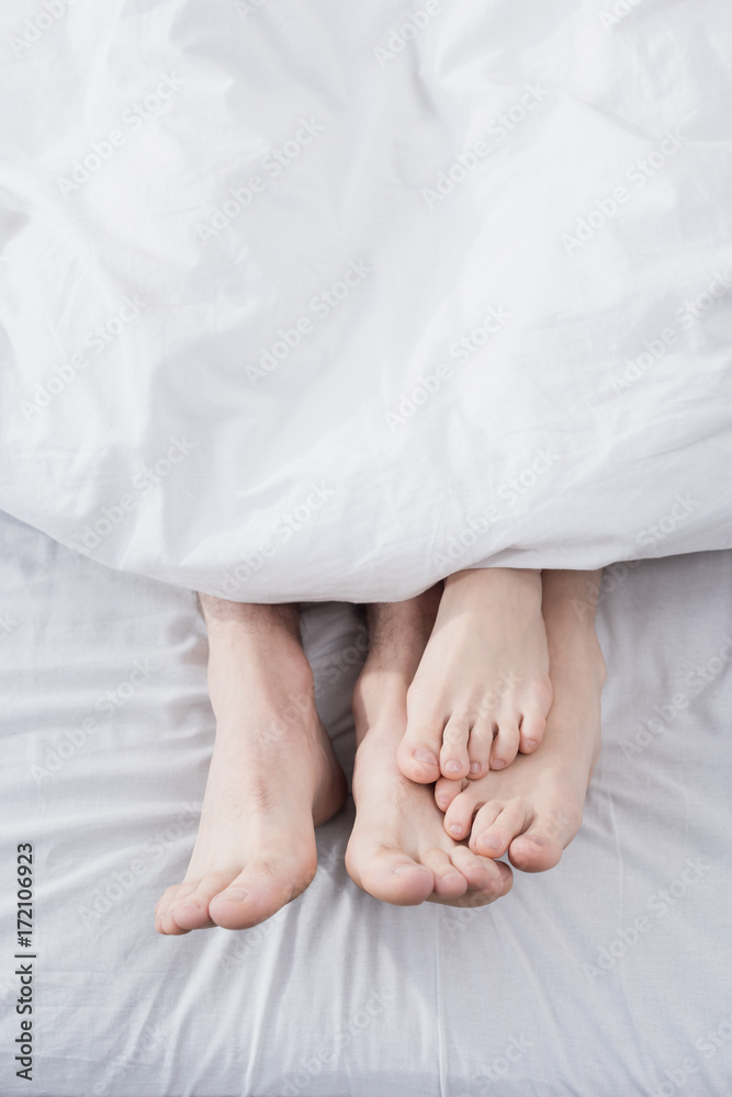 feet of couple stretching out of blanket feet of couple stretching out of blanket