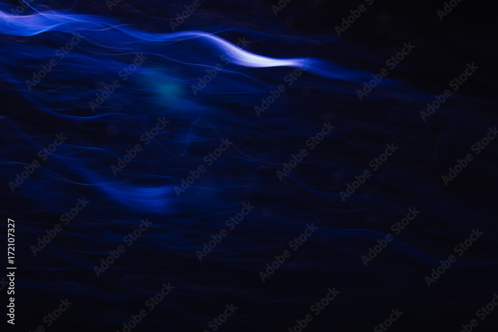 Abstract background of white waves in motion on black. Bokeh of defocused curves, blurred neon leds, similar to tobacco smoke, backdrop of addictions and acquired habits