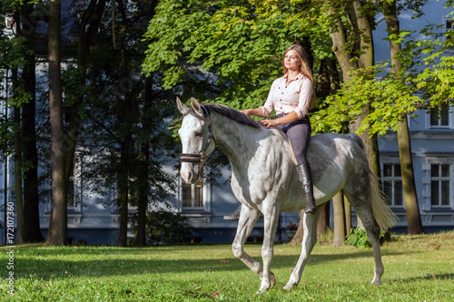 Woman riding a horse in forest or park