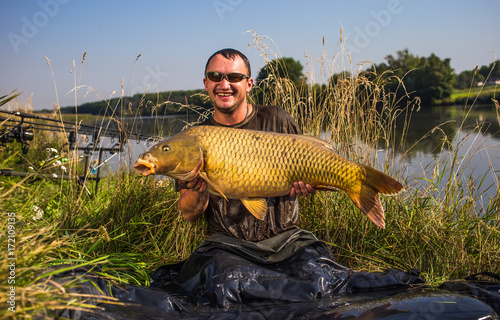 Happy angler with carp fishing trophy