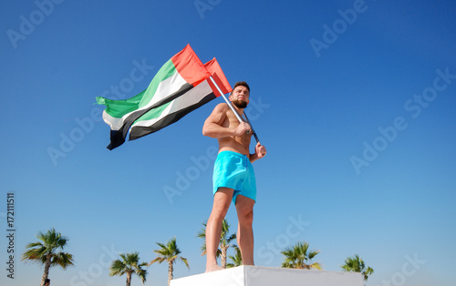 Man holding two UAE flags against the blue sky Celebration of National Day - Day of the United Arab Emirates concept photo
