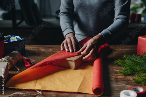 woman wrapping book as christmas gift photo