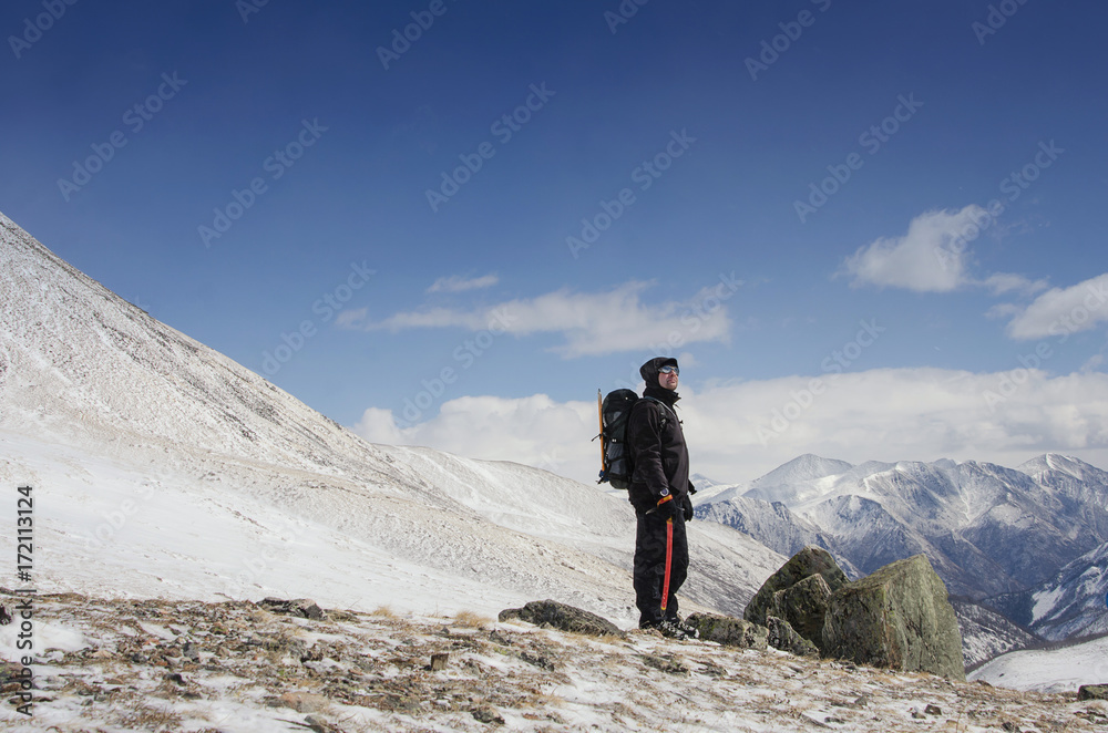 Hiker stays on a snow mountain hill and enjoy beautiful view.