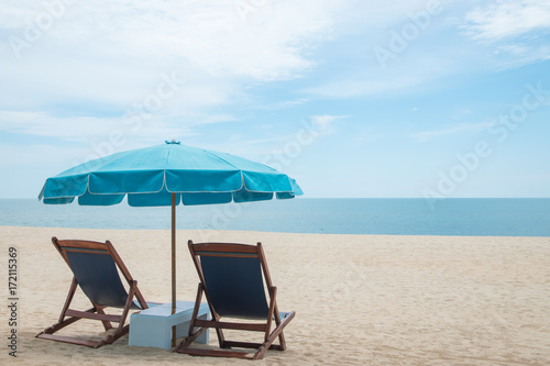 Beach chairs and blue umbrella on beautiful sand beach with cloudy and blue sky