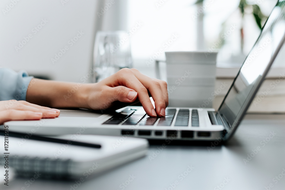 Side view and close up of woman's hands typing on laptop keyboard. Side view and close up of woman's hands typing on laptop keyboard.