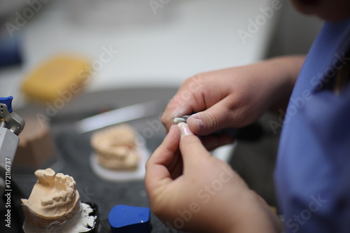 The hands of a dental technician in the process of manufacturing an individual denture photo