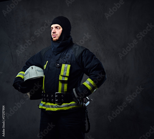 Firefighter in a uniform holds safety helmet.