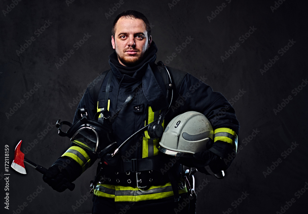 Fototapeta premium Firefighter dressed in uniform holds safety helmet.