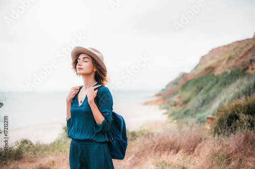 Mid adult woman in coastal setting, carrying backpack, breathing in fresh air photo