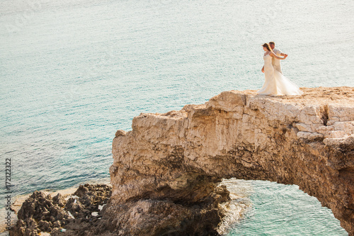 beautiful gorgeous blonde bride and stylish groom standing on rocks  on the background of a sea  wedding ceremony on cyprus.